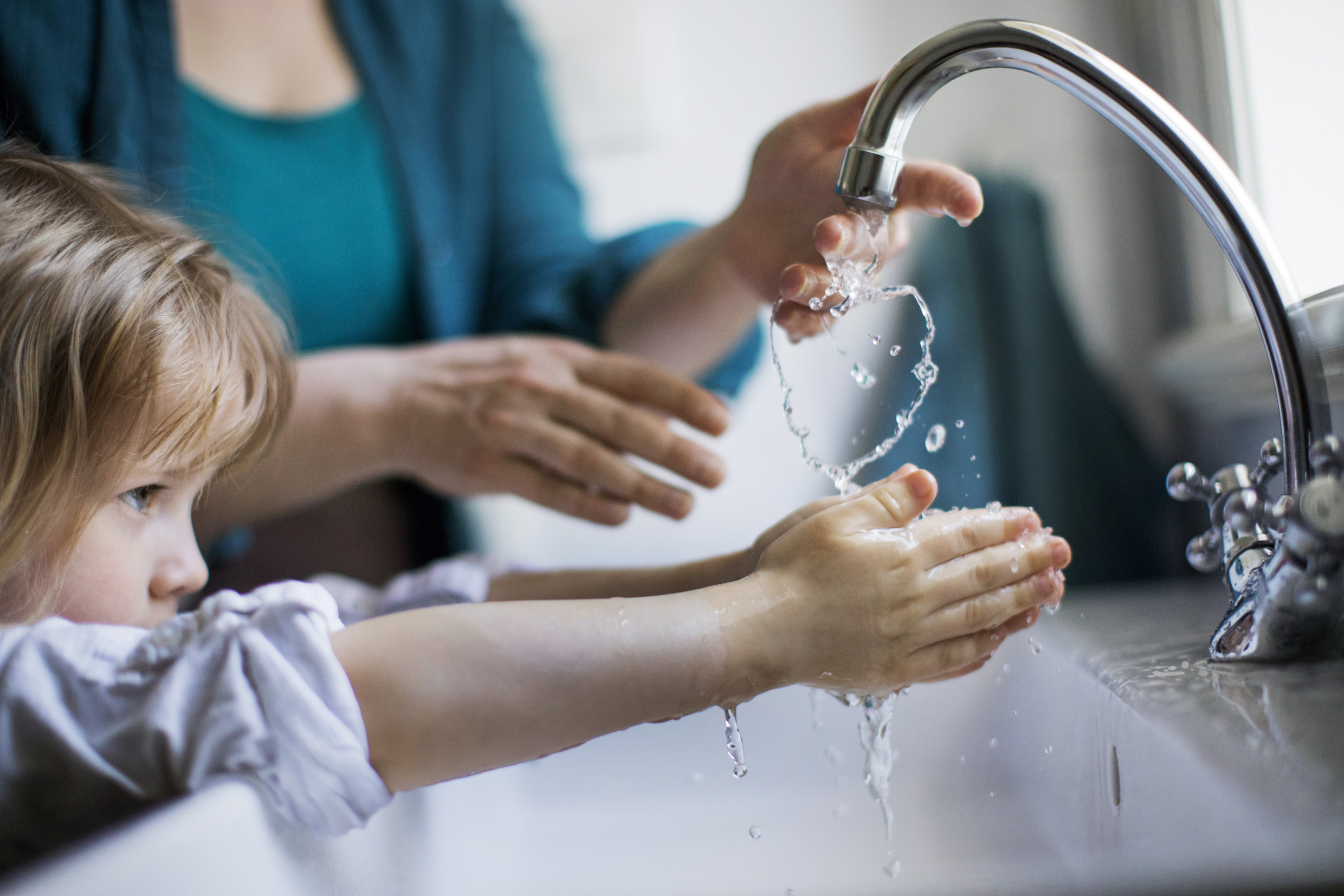 Child washing hands in tap water