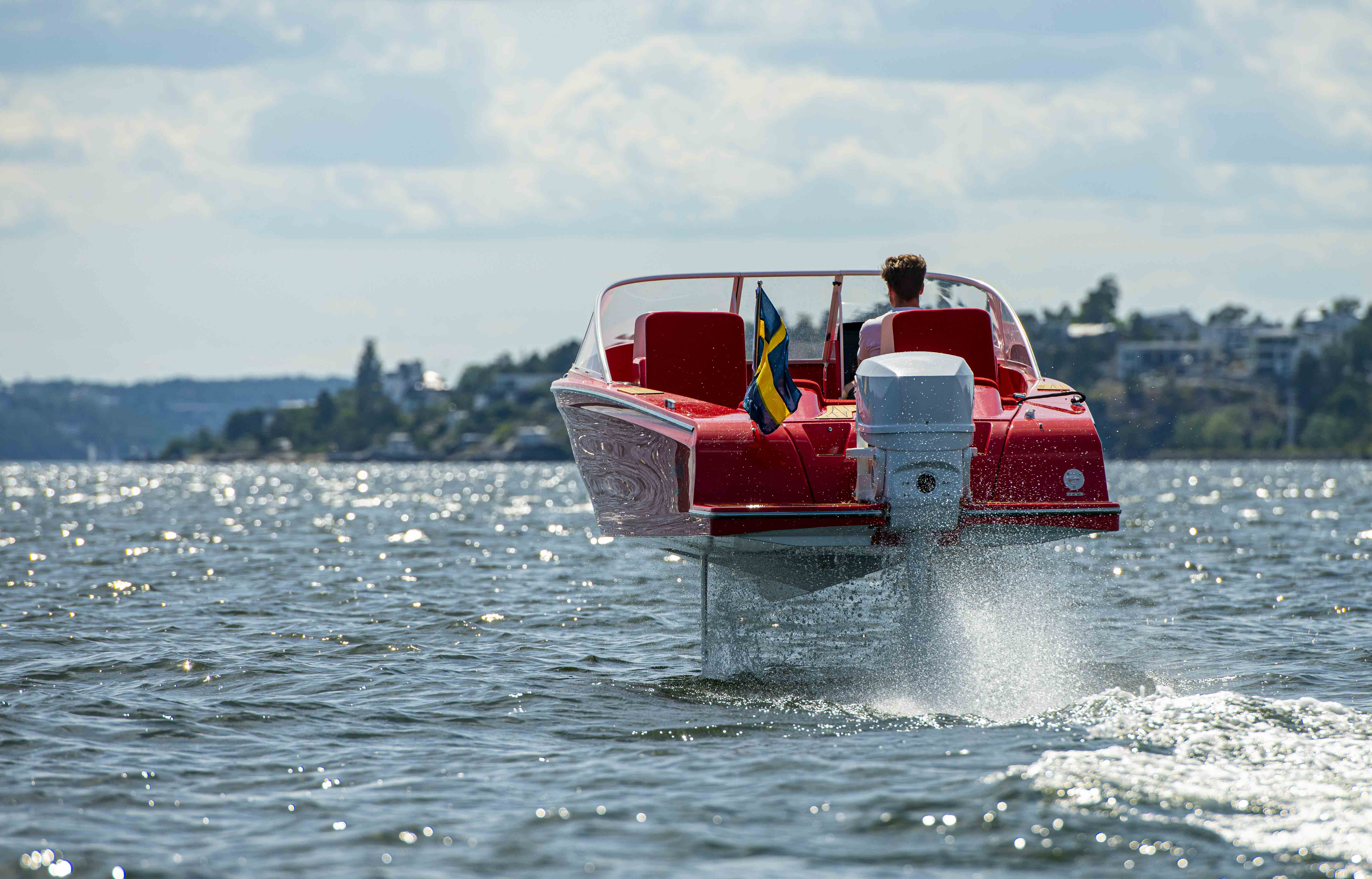 A red Candela Speed Boat driving away from camera