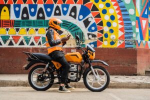 Motorcycle with person on it in front of a colorful wall